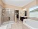 Bright bathroom featuring a glass shower and a relaxing soaking tub at 15242 Heron Hideaway Cir, Winter Garden, FL 34787