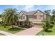 Charming two-story home with a brick driveway, beautiful landscaping, and a large palm tree at 15242 Heron Hideaway Cir, Winter Garden, FL 34787