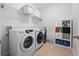 Convenient laundry room includes modern washer and dryer, storage shelves and tiled flooring at 15242 Heron Hideaway Cir, Winter Garden, FL 34787