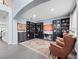 A home office with black shelving units, desk, decorative rug, and two leather chairs under recessed lighting at 15242 Heron Hideaway Cir, Winter Garden, FL 34787