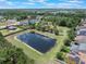 This aerial view highlights a scenic pond surrounded by lush greenery and residential homes with solar panels at 15443 Sugarcup Ct, Orlando, FL 32828