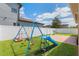 Backyard featuring a grassy yard, white fence, swing, slide and basketball hoop at 15443 Sugarcup Ct, Orlando, FL 32828
