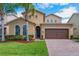 Charming home featuring a paver driveway, two-car garage and lush landscaping with palm trees at 15443 Sugarcup Ct, Orlando, FL 32828