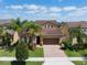 Beautiful home exhibits a paver driveway, two-car garage and a verdant lawn with mature palm trees at 15443 Sugarcup Ct, Orlando, FL 32828