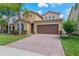 Inviting home features a two-car garage, paver driveway and a well-maintained lawn with lush landscaping at 15443 Sugarcup Ct, Orlando, FL 32828