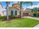 Inviting two-story home with lush lawn, palm trees, and a two car garage on a sunny day at 15443 Sugarcup Ct, Orlando, FL 32828