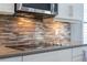 Close up of a kitchen backsplash featuring glass horizontal tiles and stainless steel cooktop at 15443 Sugarcup Ct, Orlando, FL 32828