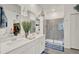 Bright bathroom features a double sink vanity with white cabinets and a gray tiled walk-in shower at 1880 Perch Hammock Loop, Groveland, FL 34736