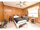 This bedroom features wood paneled walls, a ceiling fan, and an organized desk space at 2102 Urbana Ave, Deltona, FL 32725