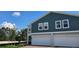 View of two-story townhomes with individual garages, set against a clear blue sky with fluffy white clouds at 222 Glass Onion Dr, Groveland, FL 34737