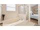 A well-lit bathroom showcasing a luxurious bathtub next to a glass-enclosed shower, adjacent to the bedroom at 232 Oxford Rd, Davenport, FL 33896