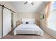 A bedroom featuring a ceiling fan, white bed and decorative chests with a sliding barn door leading to bathroom at 232 Oxford Rd, Davenport, FL 33896