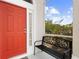 Inviting front porch featuring a vibrant red door and charming welcome bench at 232 Oxford Rd, Davenport, FL 33896