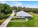 Aerial view of a landscaped home with long driveway, well kept lawn, and an open metal garage at 23203 Outback Ln, Eustis, FL 32736