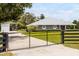 Exterior view of a grey home and open garage from behind a gated driveway at 23203 Outback Ln, Eustis, FL 32736