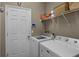 Functional laundry room with washer, dryer, shelving, and a white door at 23203 Outback Ln, Eustis, FL 32736
