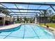 Screened pool area featuring a sparkling pool, spacious patio, lush landscaping, and ample seating at 23203 Outback Ln, Eustis, FL 32736