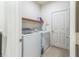 Bright laundry room equipped with a washing machine, dryer, a storage shelf, and a door at 2815 Shelburne Way, St Cloud, FL 34772