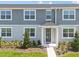 Charming townhouse with a blue front door, well-maintained landscaping, and gray siding at 2831 Camellia Flower St, Apopka, FL 32703