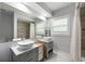 Bright bathroom featuring double sinks with modern fixtures, a large mirror, and tiled shower at 3011 Temple Trl, Winter Park, FL 32789