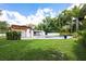 Backyard pool area with a wooden pergola, grassy lawn, and lush landscaping at 3011 Temple Trl, Winter Park, FL 32789