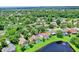 Aerial view showcases homes with pools in a lush, green neighborhood near a pond at 370 Brushwood Ln, Winter Springs, FL 32708