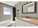 Bright bathroom features a tub with decorative tile surround, stylish vanity with granite counters and modern fixtures at 370 Brushwood Ln, Winter Springs, FL 32708