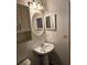 Bathroom with pedestal sink, oval mirror, and decorative wall lights at 3700 Plantation Blvd, Leesburg, FL 34748