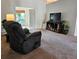 Cozy living room with recliner, TV, shelving unit, and view to the enclosed patio at 3700 Plantation Blvd, Leesburg, FL 34748