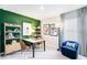 Home office with green accent wall, decorated with desk, shelves, paintings and a blue chair at 4760 Yellow Elder Way, Kissimmee, FL 34758