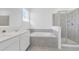 Bathroom with dual sinks, a soaking tub, and a glass-enclosed shower, all adorned with neutral-colored tiles at 502 Bogey Dr, Davenport, FL 33896