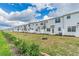 A row of modern white townhomes with newly planted trees and landscaped yards, perfect for a stylish and comfortable lifestyle at 502 Bogey Dr, Davenport, FL 33896