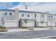 Modern townhouses show stone accents, individual garages, brick driveways and landscaping against a blue sky at 502 Bogey Dr, Davenport, FL 33896