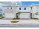 New townhouse exterior shows modern architecture with brick driveway, stone accents, attached garage and tasteful landscaping at 502 Bogey Dr, Davenport, FL 33896