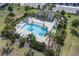 Aerial view of a community pool area featuring lounge chairs, umbrellas, and palm trees for resort-style living at 5214 Dragonfly Dr, Wildwood, FL 34785