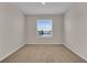 Bright, carpeted bedroom featuring a large window with outside views at 5214 Dragonfly Dr, Wildwood, FL 34785