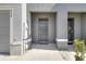 Close-up of the gray front door with a covered porch and well-maintained surroundings at 5214 Dragonfly Dr, Wildwood, FL 34785