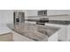 Elegant kitchen island with gray granite countertops and a stainless steel sink and appliances at 5214 Dragonfly Dr, Wildwood, FL 34785