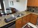 Well-lit kitchen with granite countertops, wood cabinets, and stainless steel sink at 7518 Seven Eagles Way # 201, Reunion, FL 34747