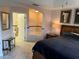 A well lit Main Bedroom with a tiled floor, ensuite bathroom, tub, and large bed with side tables at 7518 Seven Eagles Way # 201, Reunion, FL 34747
