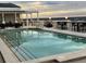 Rooftop pool surrounded by tables, chairs and outdoor bar, with a beautiful sunset at 7518 Seven Eagles Way # 201, Reunion, FL 34747