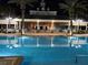 Nighttime view of an illuminated pool and the building, surrounded by palm trees at 7518 Seven Eagles Way # 201, Reunion, FL 34747
