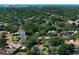 An aerial view showcases the community with mature landscaping, nearby city skyline, red pin, and water tower at 7703 Pine Vista Ct, Orlando, FL 32819