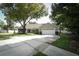 Attractive single-story home with a paved driveway, manicured lawn, and mature trees enhancing curb appeal at 7703 Pine Vista Ct, Orlando, FL 32819