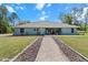 Back exterior of a light blue single-story home, with manicured lawn and landscaping at 8660 Sw 137Th Ct, Dunnellon, FL 34432