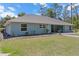 View of the back exterior featuring a well-maintained lawn, landscaping, and the light blue home at 8660 Sw 137Th Ct, Dunnellon, FL 34432