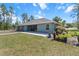 Well-manicured backyard showcasing lush lawn, landscaping, and a modern blue home at 8660 Sw 137Th Ct, Dunnellon, FL 34432