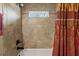 Tiled shower and tub area with small window and decorative curtain at 8660 Sw 137Th Ct, Dunnellon, FL 34432