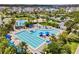 Aerial view of a community pool area with multiple pools, lounge chairs, and lush landscaping at 8679 Laureate Blvd, Orlando, FL 32827