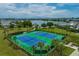 Aerial view of tennis courts and lush landscaping surrounded by community homes with a picturesque lake in the background at 8679 Laureate Blvd, Orlando, FL 32827